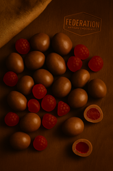 Chocolate candies with red berries on a wooden surface, featuring the Federation Artisan Chocolate logo.