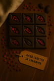 Dark chocolate bars with Freeze Dried raspberry on a wooden surface, accompanied by a 'Hand Crafted in Tasmania' tag.