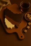 Tassie shaped Chocolate bar with a scoop on a wooden board, accompanied by a glass of whiskey and small bowls of cookies.