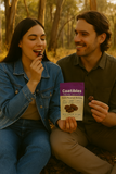Two people sitting outdoors, one holding a 'Coatibles' snack package.